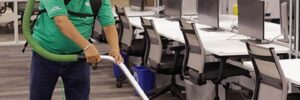 An ABS Cleaners employee vacuums an office conference room