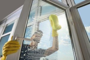 A man washing the window of a door outside a business